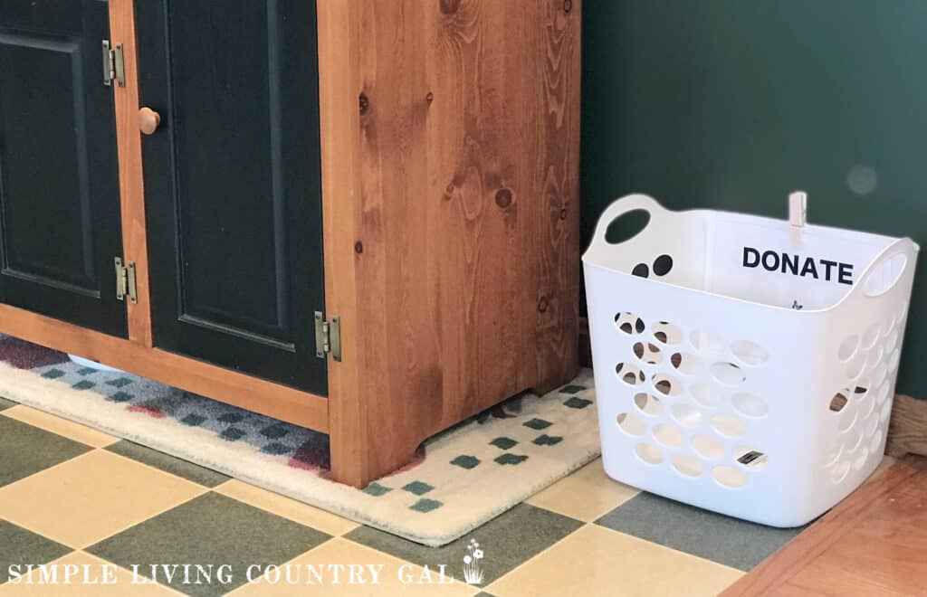 a white laundry basket with a DONATE label on it, sitting on the floor in a kitchen