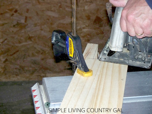 A hand saw cutting a piece of wood near to a vice clamp