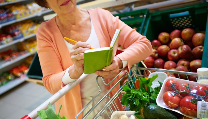 A shopper in a grocery store crosses items off a list. Lists are helpful in having a stress-free Thanksgiving. 