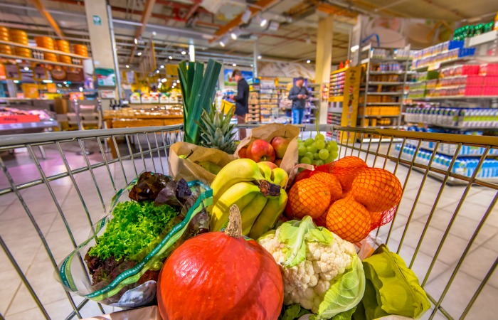 a shopping cart in a store full of produce