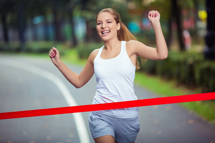 a happy women running up to red finish line tape