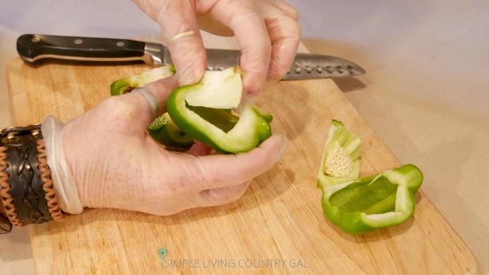Coring a pepper with gloves on for protection. How to freeze peppers so you always have a supply of healthy and delicious peppers in your freezer when you need them. #howtofreezepeppers #canning #foodpreservation