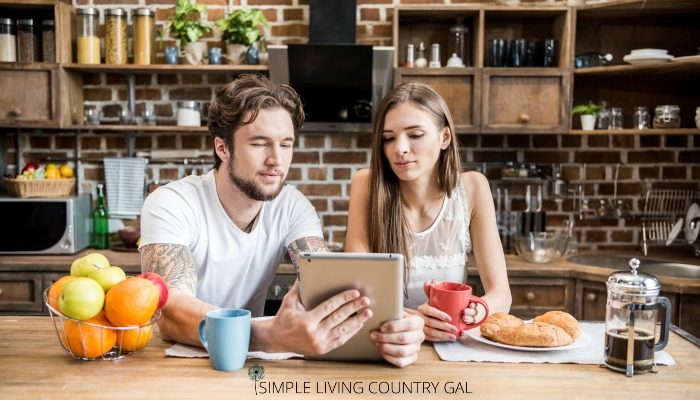 A couple looking at an ipad in a kitchen planning out projects 
