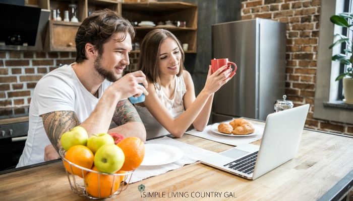 A couple planning out projects for their homestead in a kitchen with a laptop