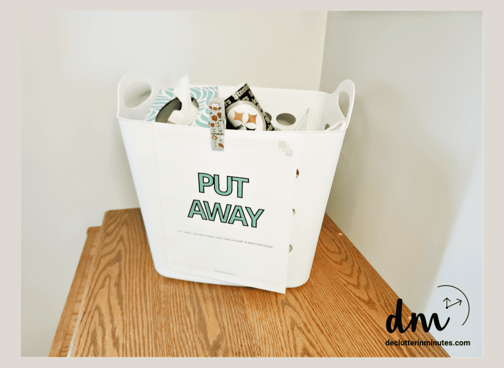 a white basket with a label that says put away on the front filled with clutter