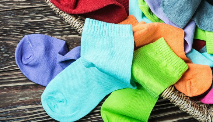 a pile of brightly colored socks on a wood table