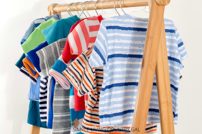 A collection of childs shirts hanging on a wooden rod