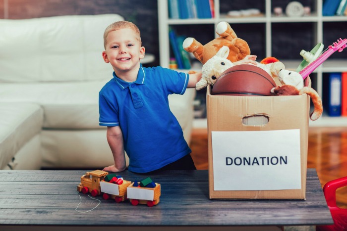 A child puts some toys into a donation box as he helps his family declutter. 