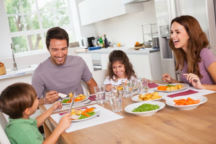 a young family sitting down to eat dinner