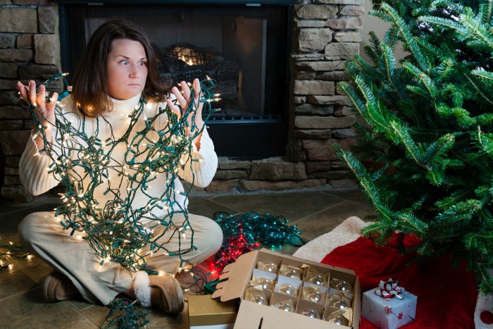 A woman sits frustrated with tangle holiday lights. Learn how to tame these string lights.