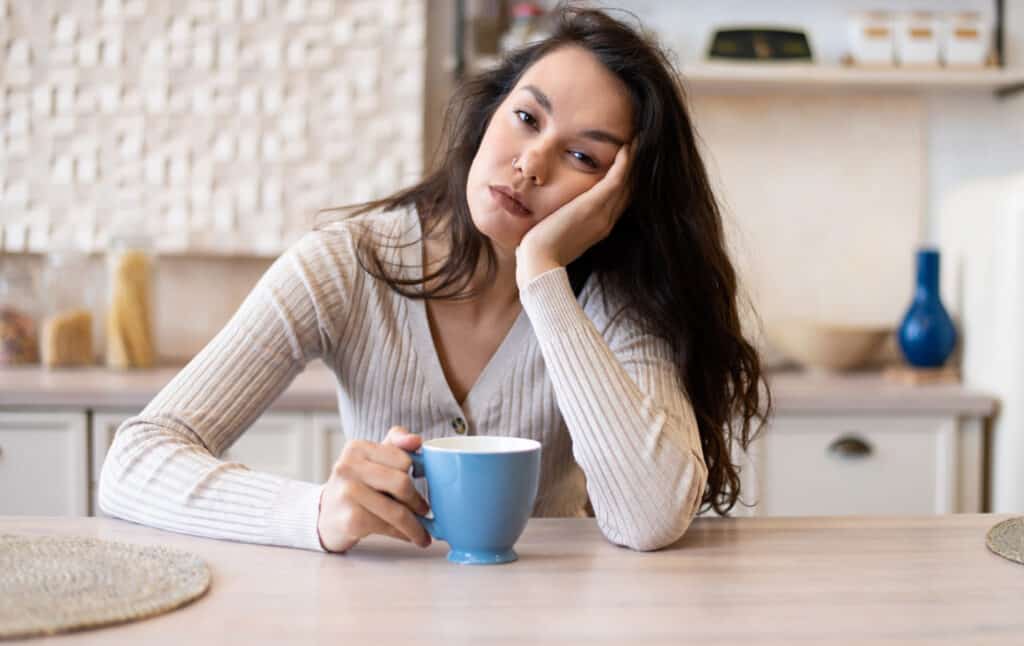 tired woman holding a coffee cup needing a morning routine