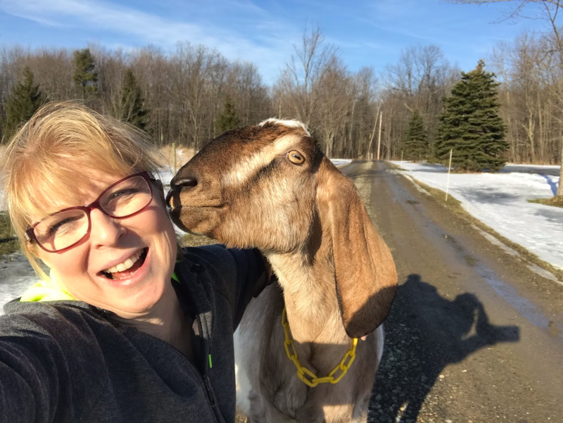 a goat nibbling on a woman's ear