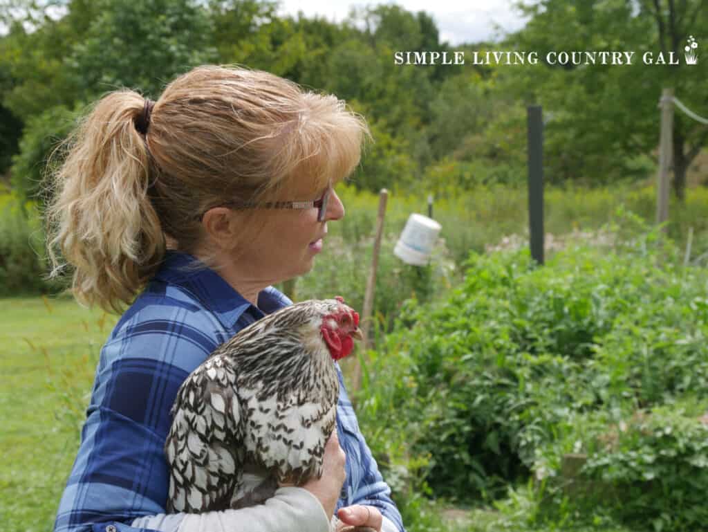 girl holding a chicken looking at a vegetable garden
