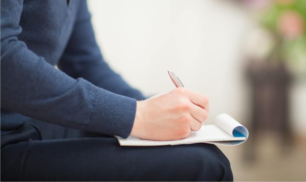 a woman sitting in a room making a list on her lap