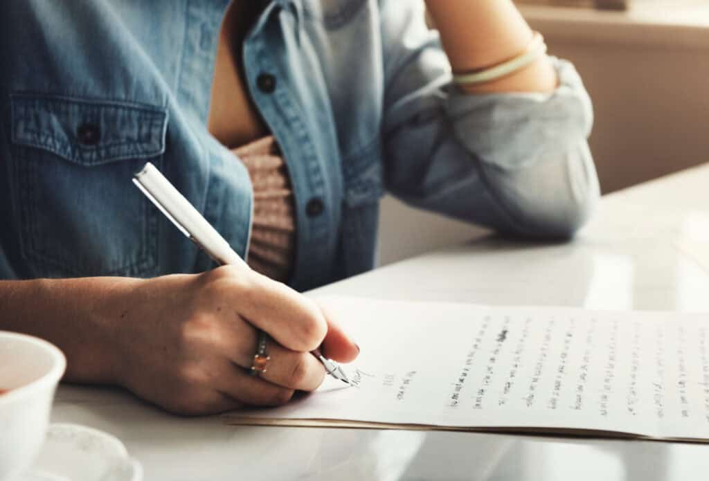 a woman in a jean jacket writing a letter