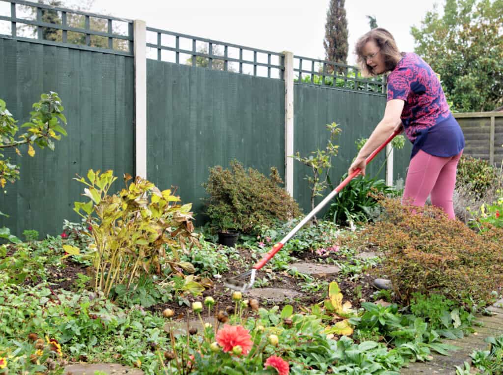 woman using a hoe in a flower garden