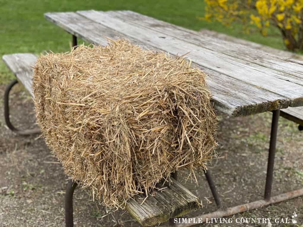 a straw bale sitting on a picnic table bench 