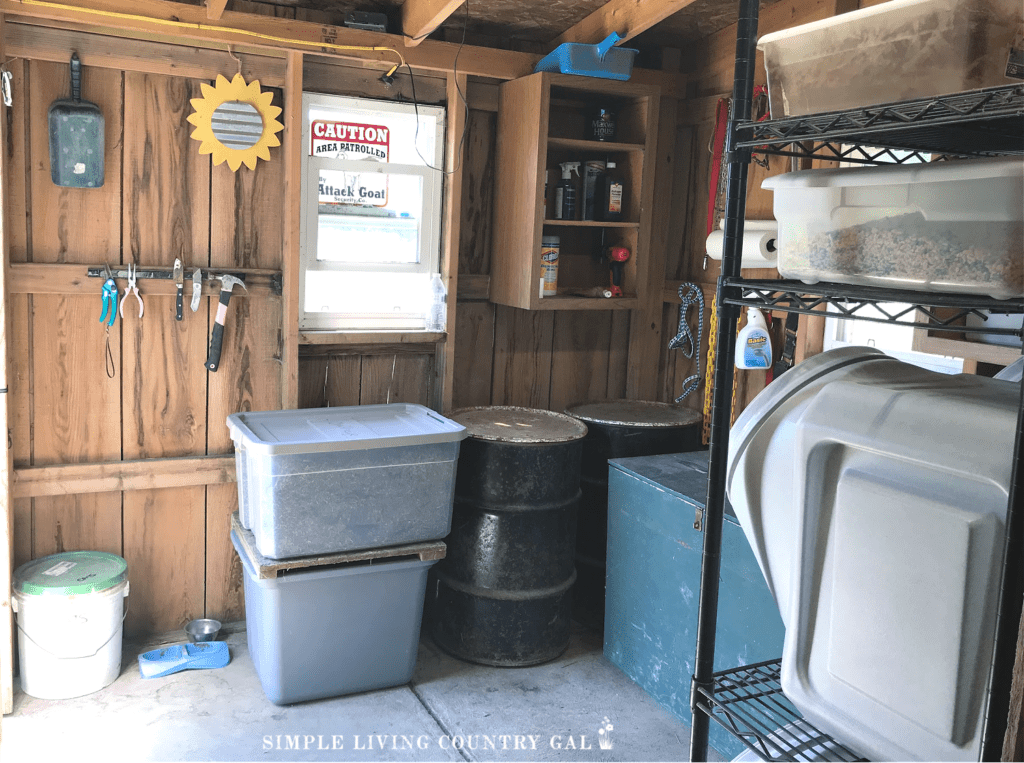 a large feed room with totes, barrels, and shelves of livestock feed and supplies