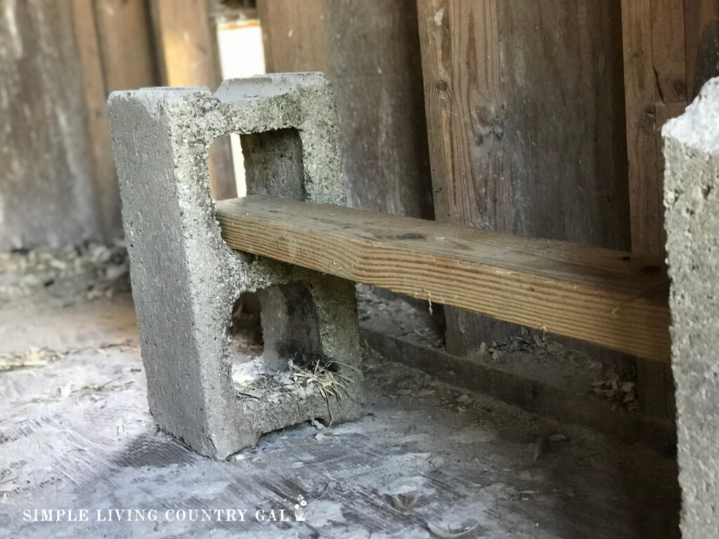 cinder block with a board through it as a chicken roost in a coop