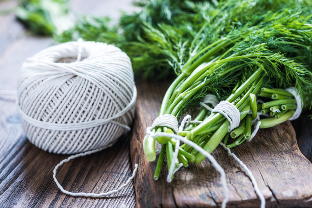 A popular method to dry herbs includes tying the stems together with string and hanging the herb bundles up to remove moisture. 