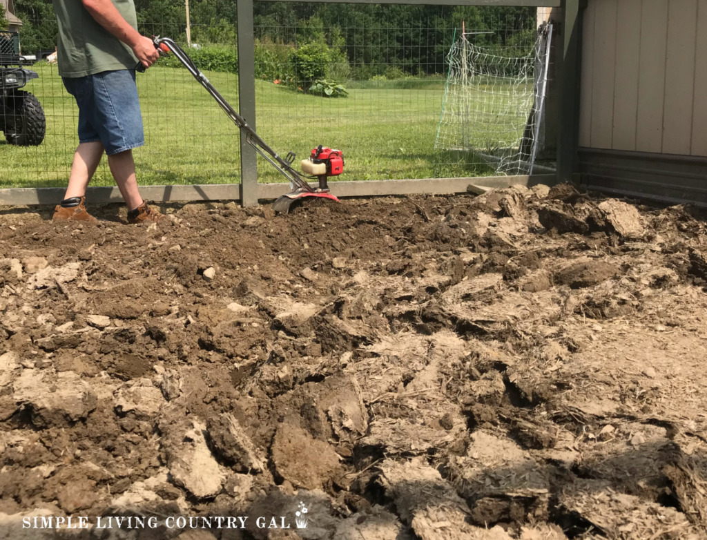 a man rototilling a chicken run