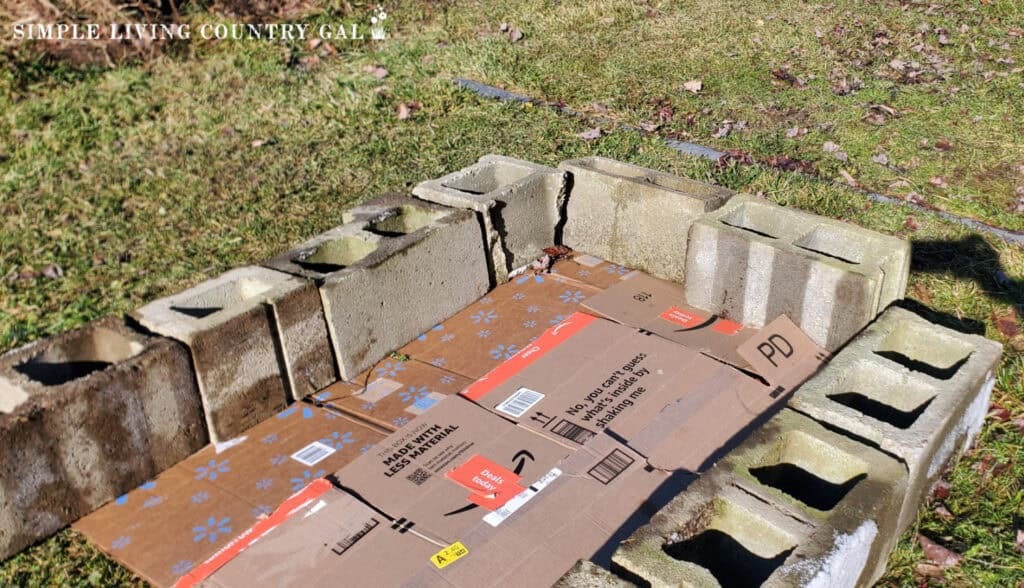 a cinder block frame with sheets or cardboard on the ground in a yard