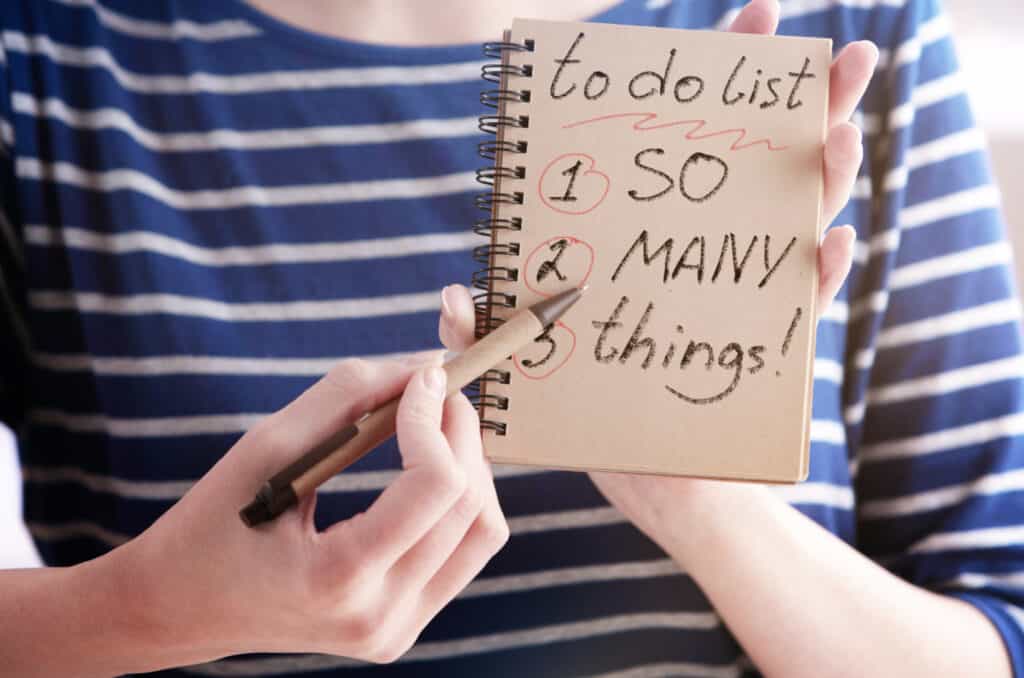 Close up of woman hands writing to do list in spiral notepad