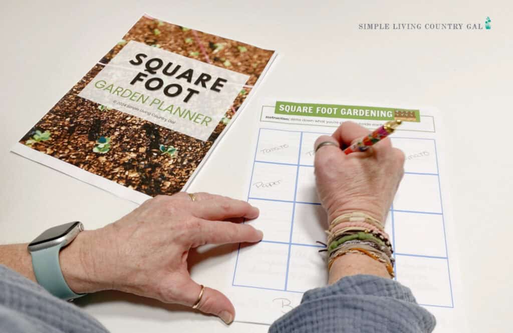 woman writing plants on a grid for a square foot garden layout 