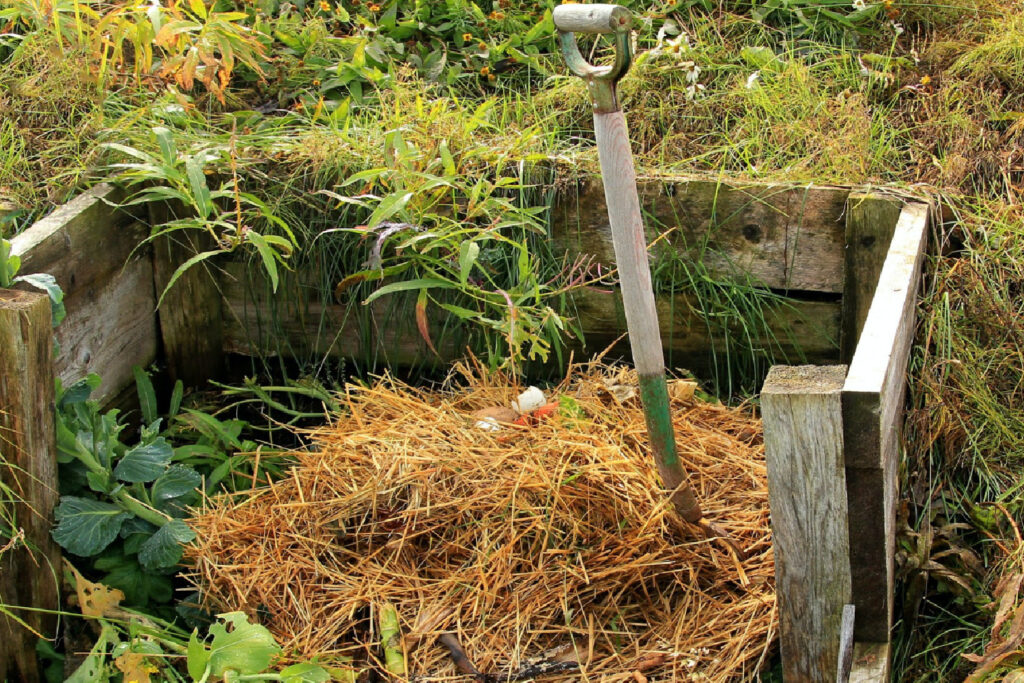 pitchfork in a pile of straw in a diy compost bin