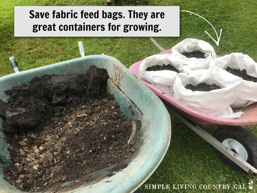 a wheelbarrow of soil next to bags of soil 