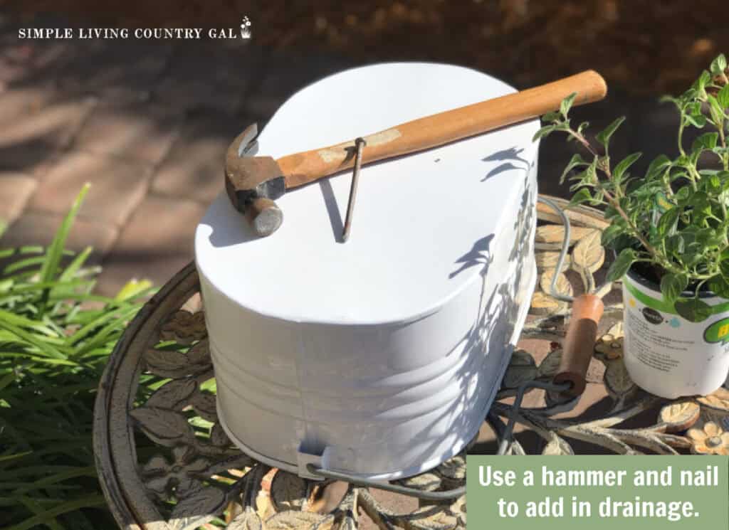 a hammer sitting on top of a metal container near to a nail to add holes for drainage