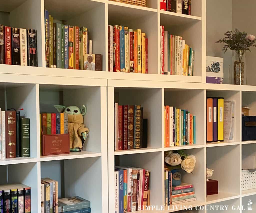 a white bookcase full of books on gardening, homesteading, and others