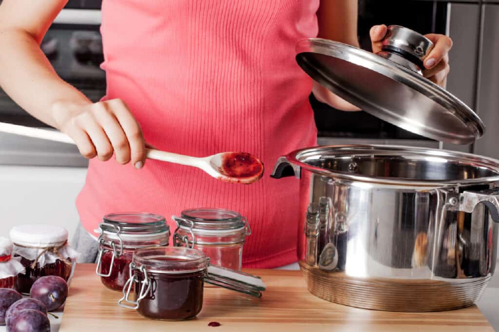 woman spooning jam into canning jars vcxz