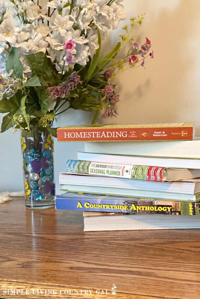 a stack of top homesteading books next to flowers