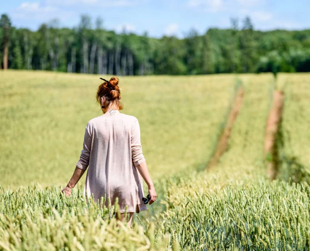 a woman walking in a field living a simple life