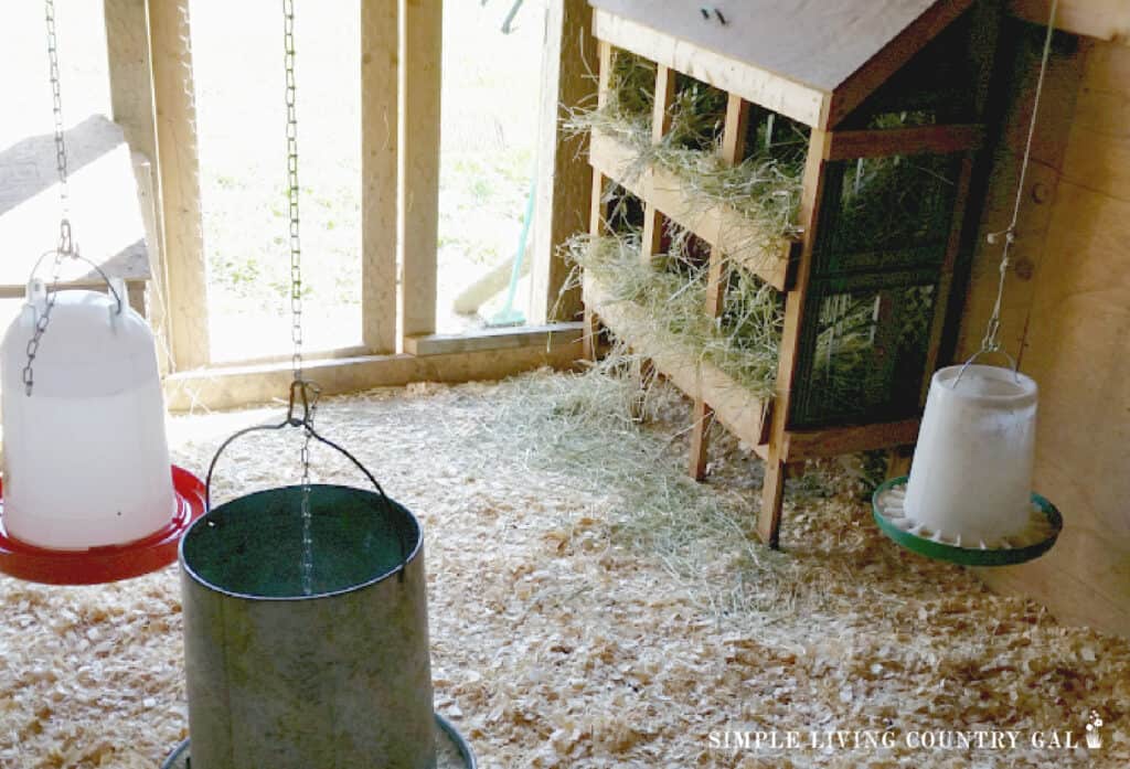 the inside of a chicken coop with nesting boxes and feeders hanging