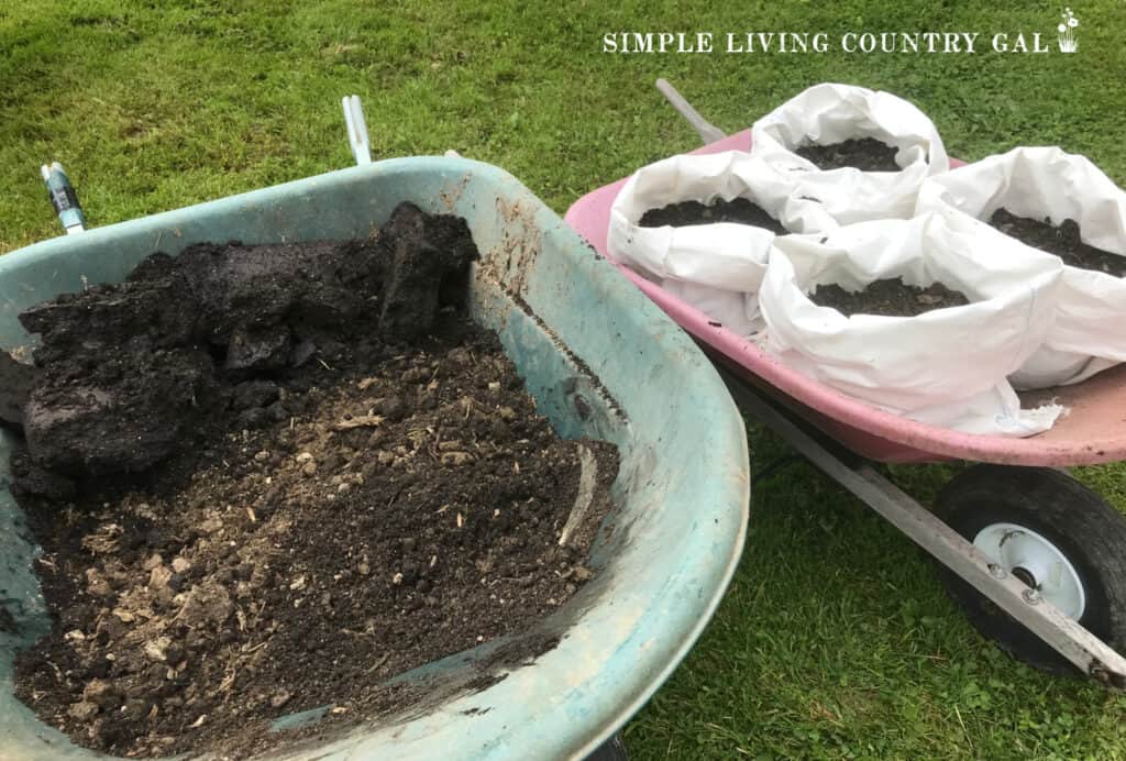 a wheelbarrow of soil next to bags of soil