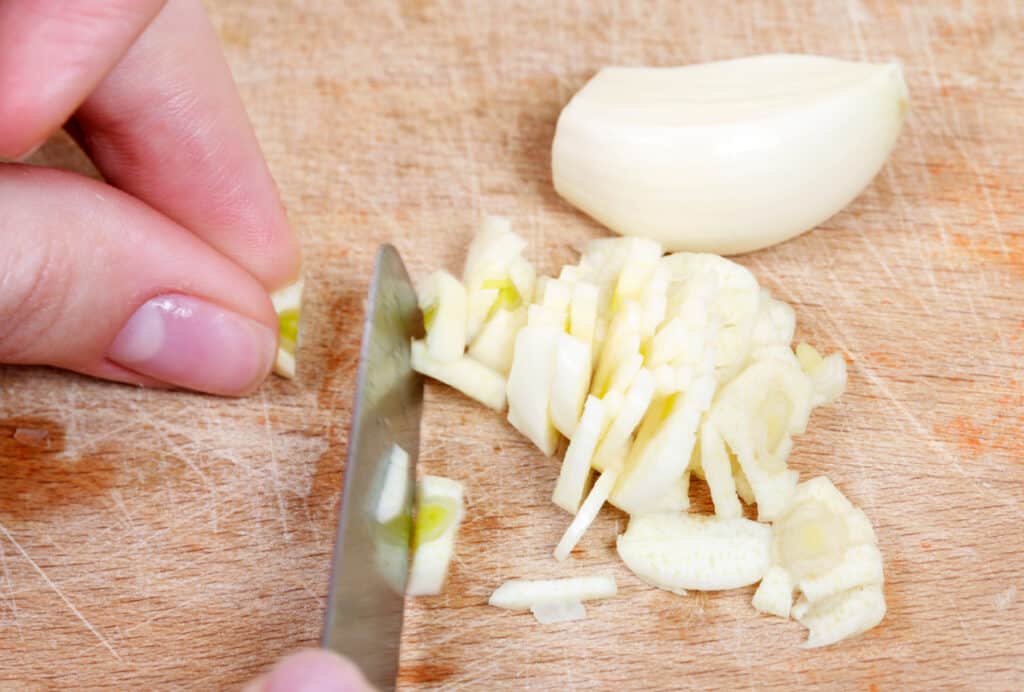 close up on hands chopping up a clove or fresh garlic