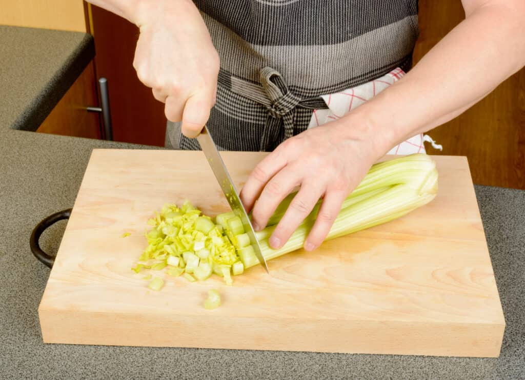 hands chopping celery on a cutting board