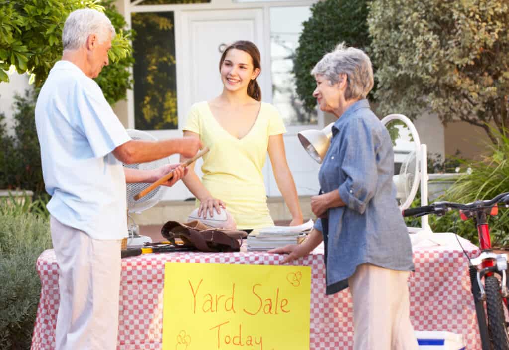 2 people shopping at table at a yard sale