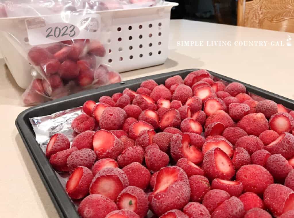 a cookie sheet of frozen berries with freezer bag of berries in the background