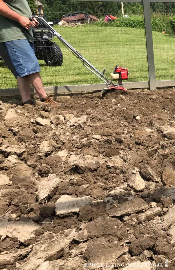 a man tilling up soil with a red rototiller