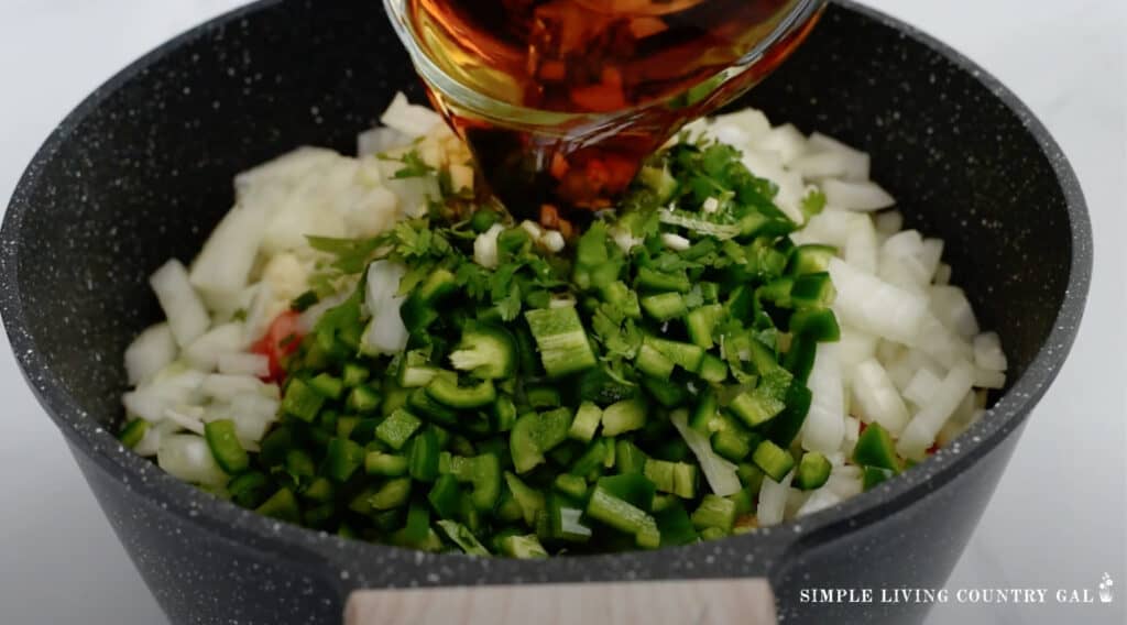 apple cider vinegar being added to a pot of salsa ingredients