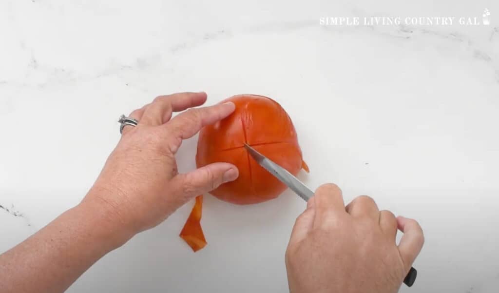 hands peeling a tomato with a knife