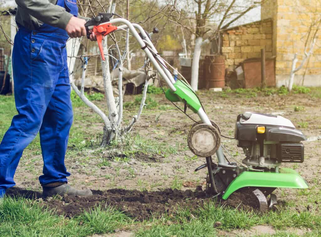 Man working in the spring garden with tiller machine.