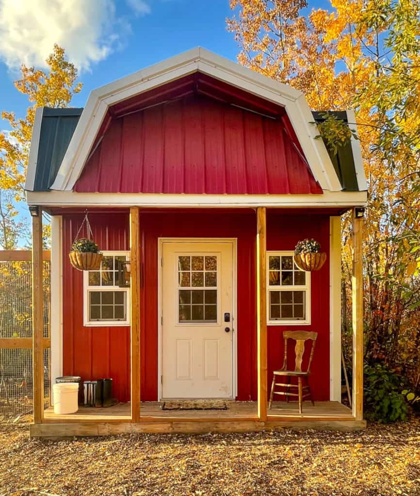 a red chicken coop with a front porch