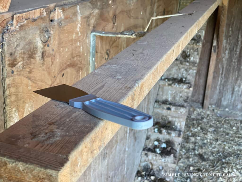 a scraper lying on a chicken roost in a coop