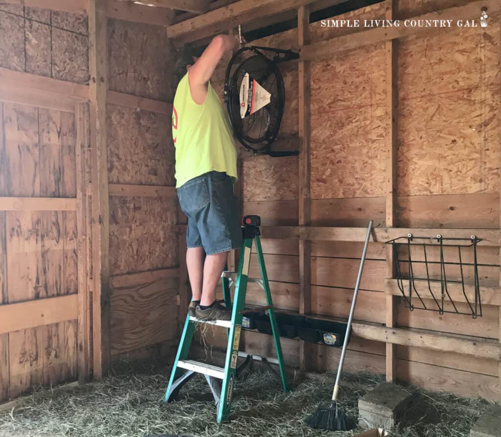 man installing a fan in a barn