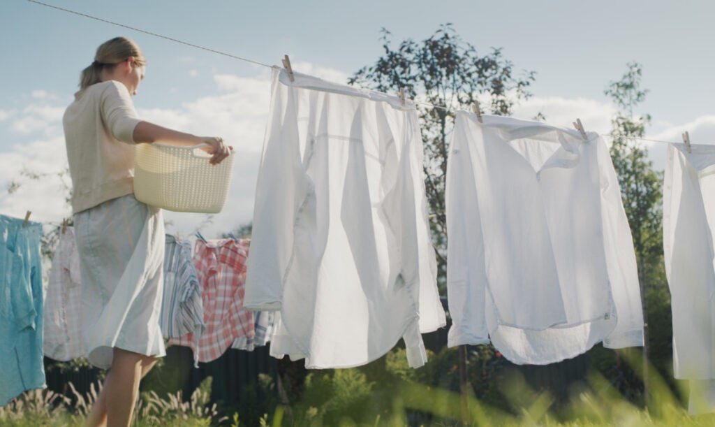 Woman watching bed linens dry in the backyard of the house.