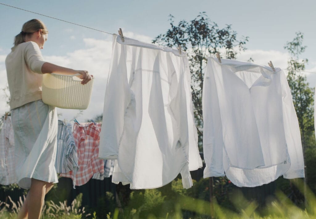 Woman watching bed linens dry in the backyard of the house.